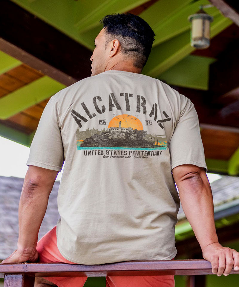 Person wearing a t-shirt with 'Alcatraz' graphic design outdoors. View 2