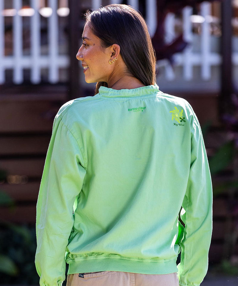 Woman wearing a bright green jacket with a logo on the back, standing outdoors. View 3