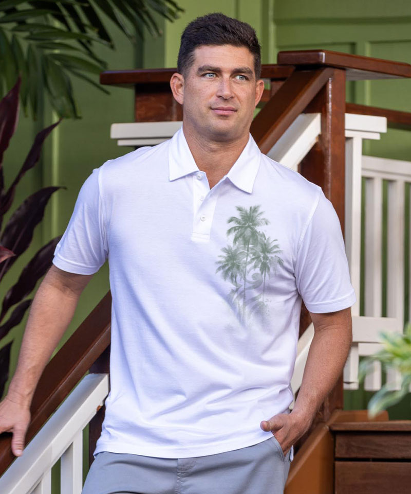 Man wearing a light blue polo shirt with a palm tree design, standing on a staircase. View 2