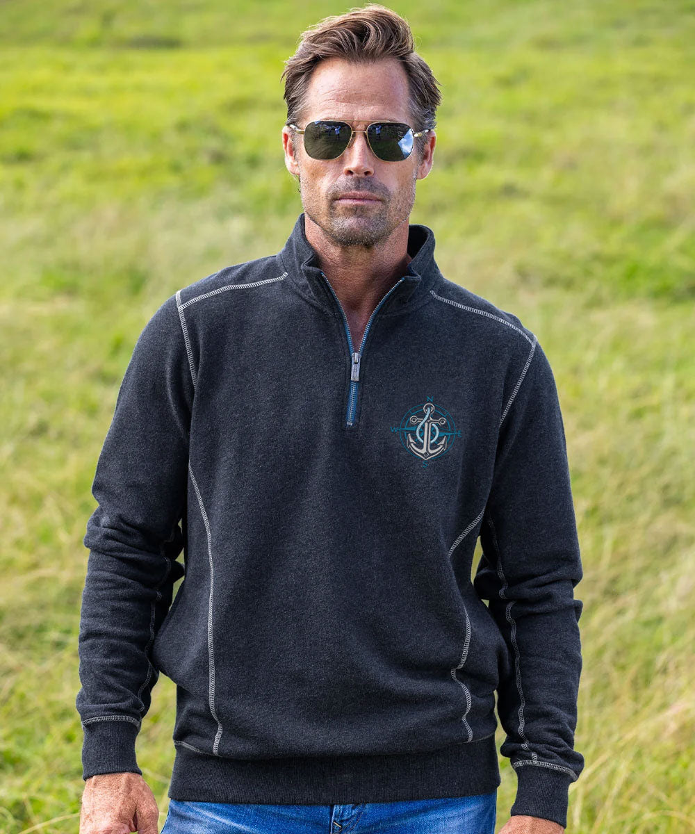 A man  wearing a dark charcoal gray quarter-zip fleece pullover with light gray contrast stitching, standing in a grassy field. View 2