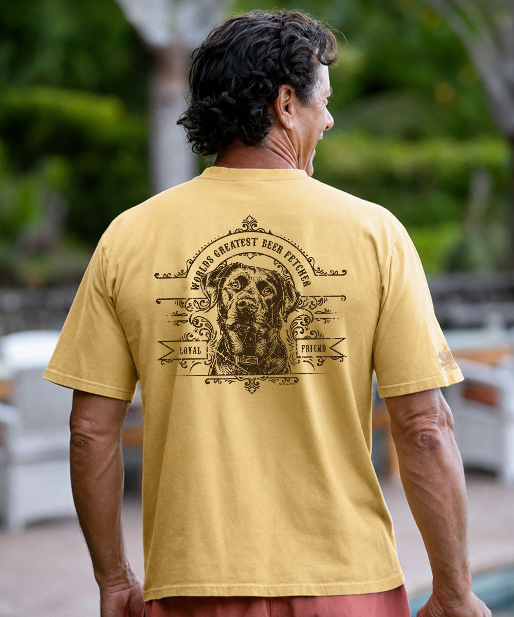 A man viewed from behind wearing a mustard yellow t-shirt with a large black graphic print of a dog on the back, set against a blurred outdoor background. View 2