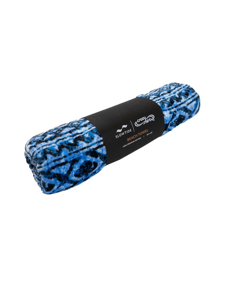 A rolled-up fleece blanket with a blue and black abstract pattern, wrapped in a black paper band featuring the Scarftop and Scorpion logos. View 2