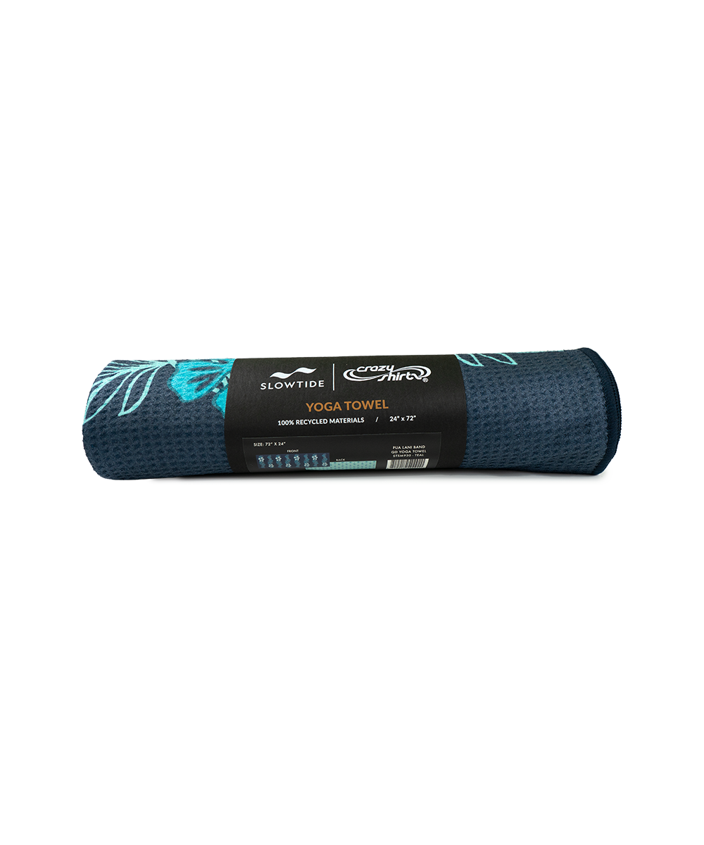 A rolled-up dark teal yoga towel with a black paper band label around the middle, featuring the SlowFit and CrossFit Starter logos. The towel has a textured surface and a subtle light teal leaf pattern on one end. View 3