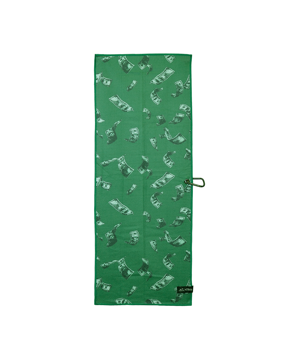 A green rectangular towel featuring an all-over print of dollar bills in green and white, with a small black brand tag at the bottom right and a metal loop on the side, shown against a plain white background. View 2