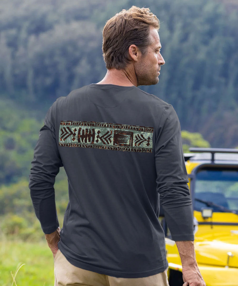 A man wearing a dark gray long-sleeve shirt with a brown tribal-style graphic print across the upper back, standing outdoors in front of a forest and a yellow vehicle. View 3