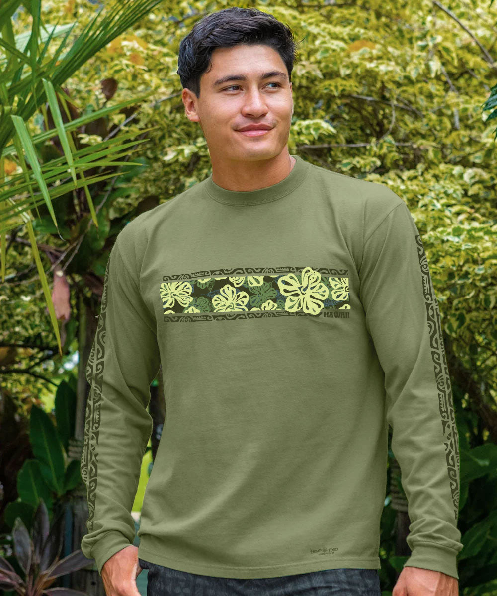 A man wearing an olive green long-sleeve shirt with a yellow-green floral pattern across the chest and matching patterns down the sleeves, set against a lush green outdoor background. View 2