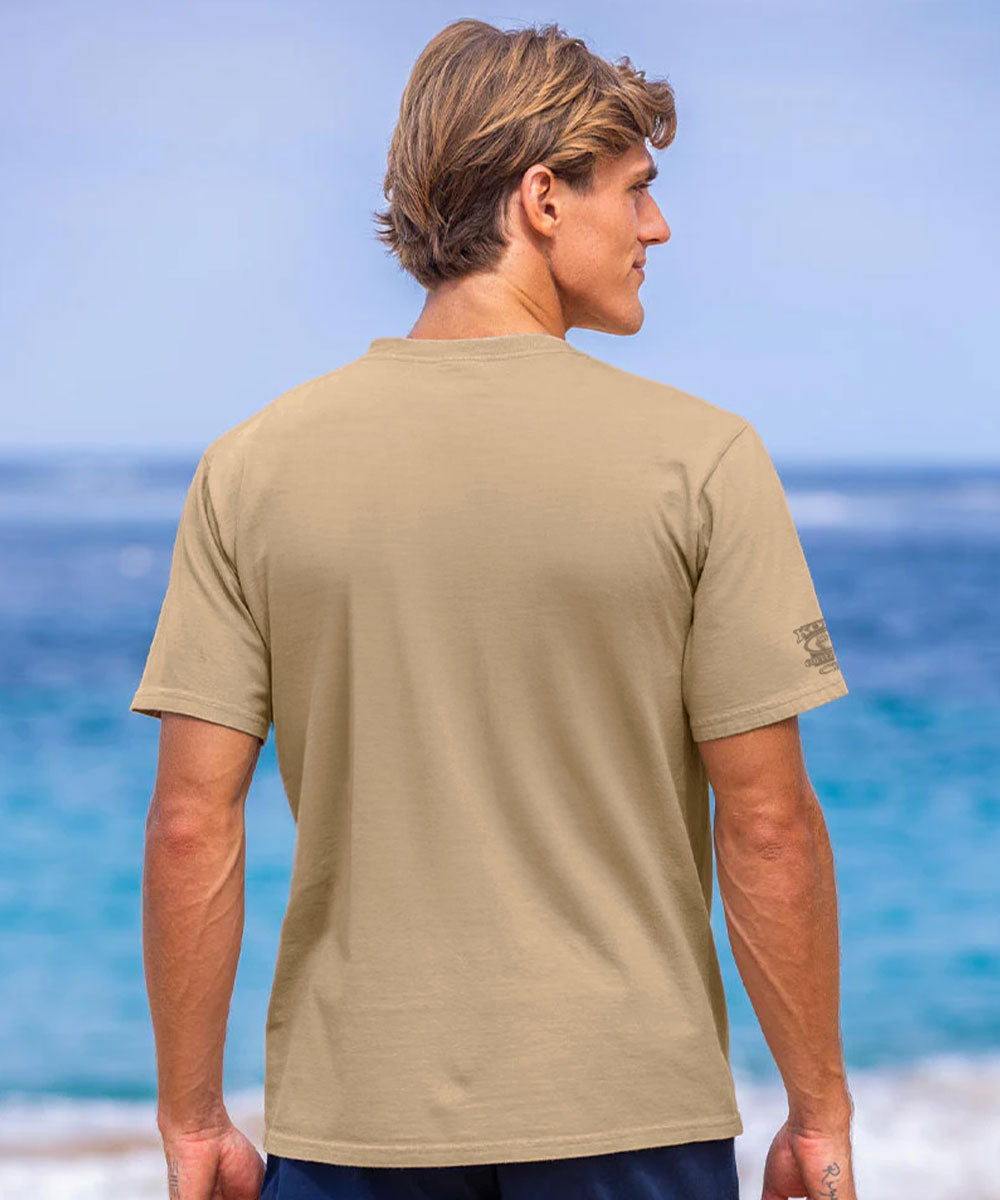 Man wearing a beige t-shirt standing on a beach with ocean view View 3