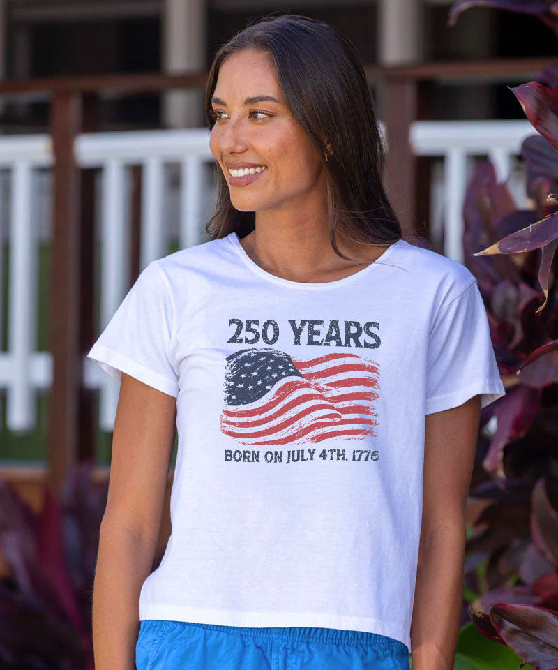 Woman wearing a white t-shirt with a graphic design and text, standing outdoors. View 2