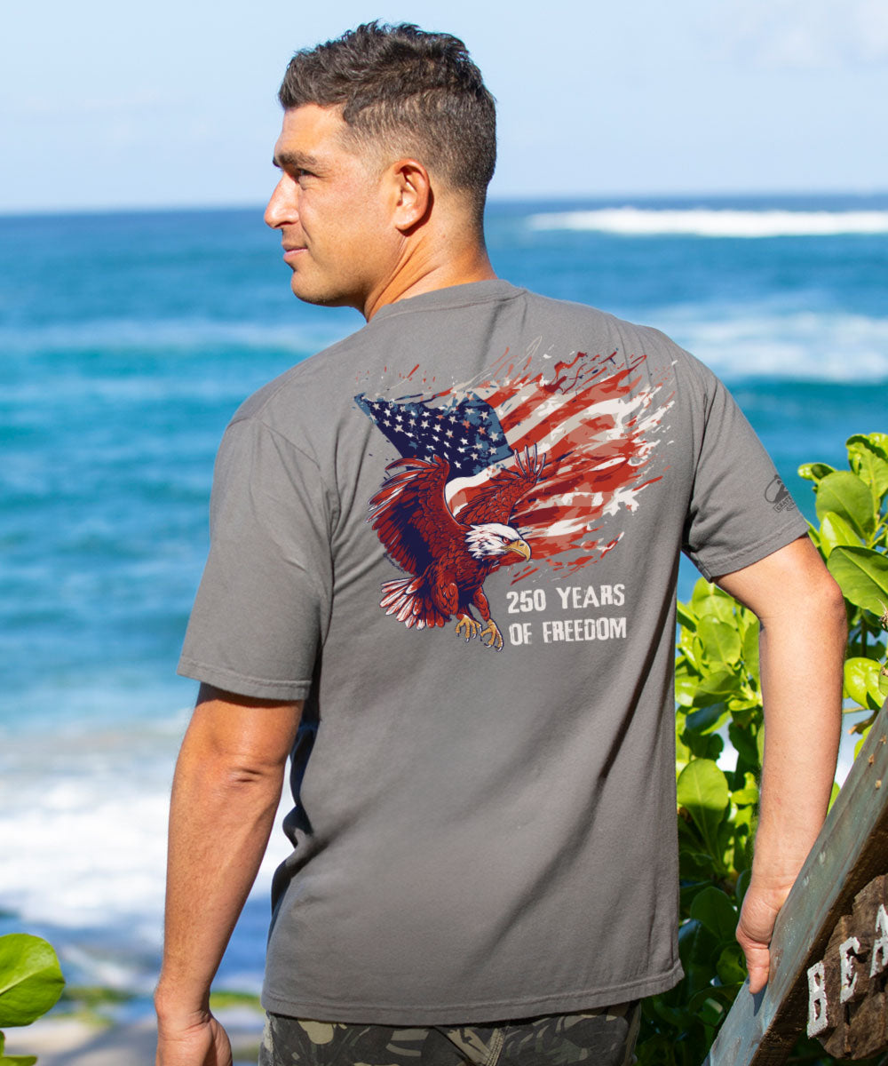 Man wearing a t-shirt with an eagle and American flag design by the ocean.