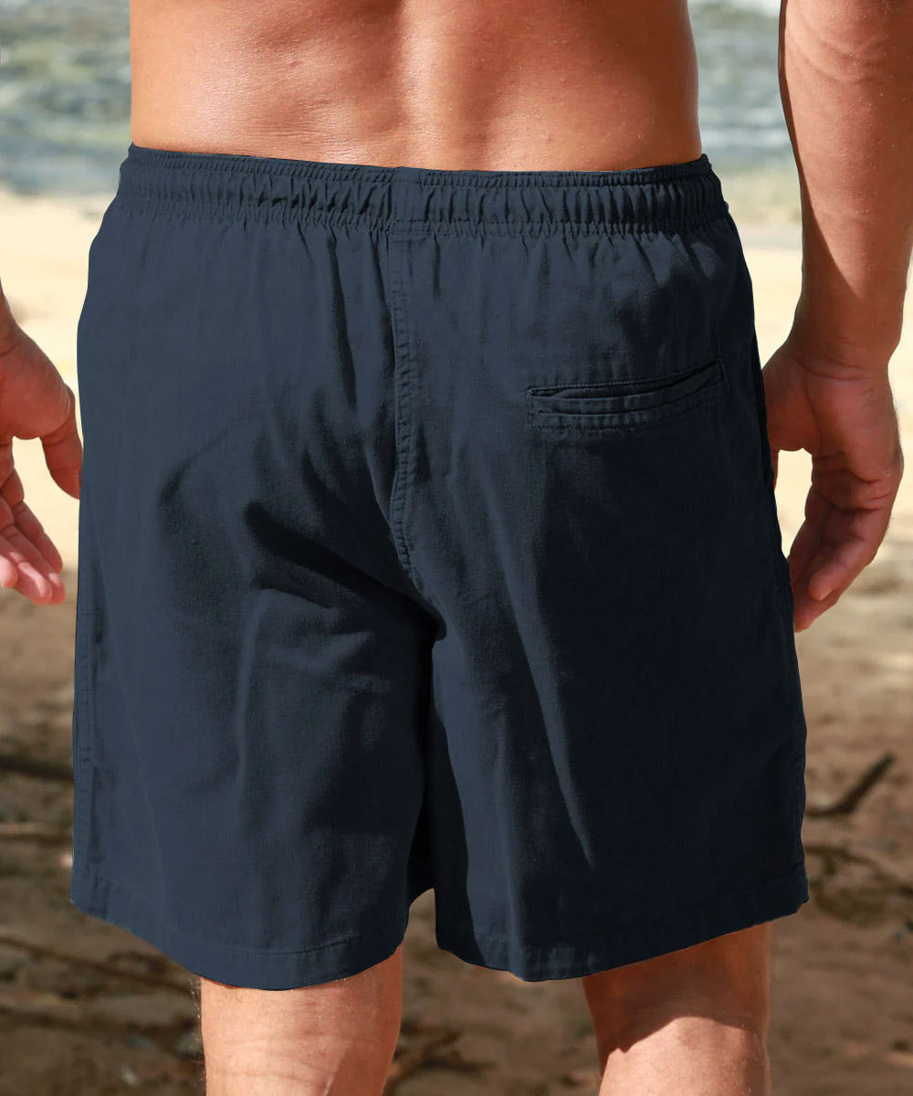 Person wearing navy blue shorts on a beach. View 3