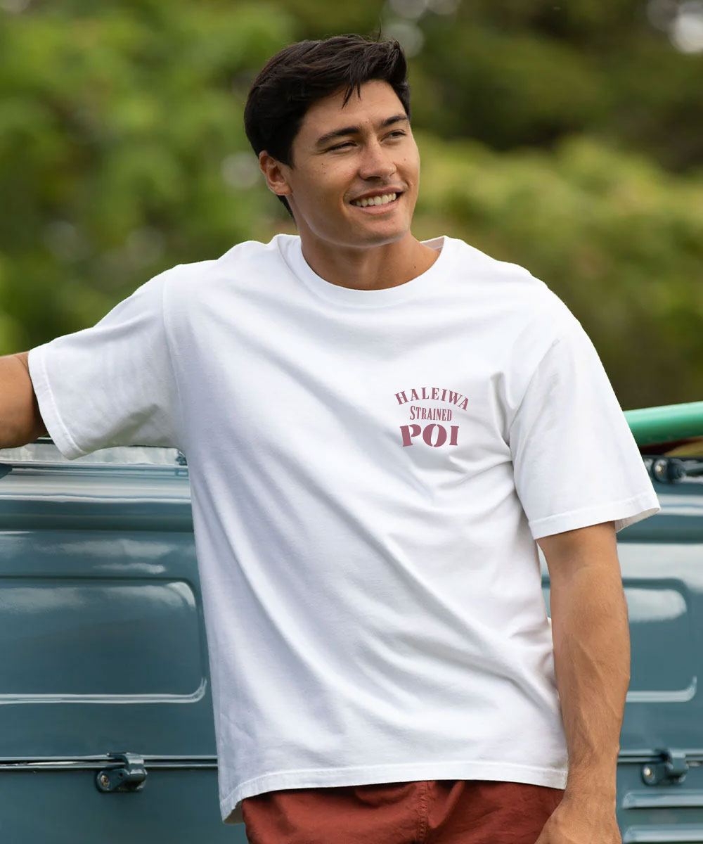 Man wearing a white t-shirt with a small graphic on a blurred outdoor background View 3