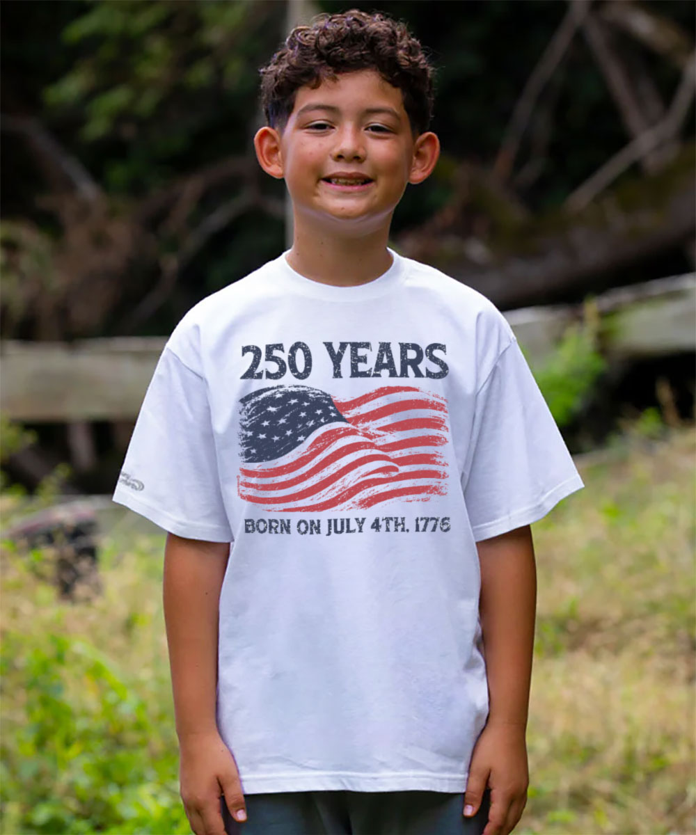 Child wearing a white t-shirt with '250 Years' and an American flag design, standing outdoors. View 2