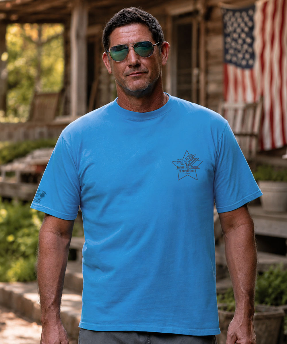 A man wearing a bright blue crewneck t-shirt with a dark gray star graphic on the left chest, standing outdoors View 3