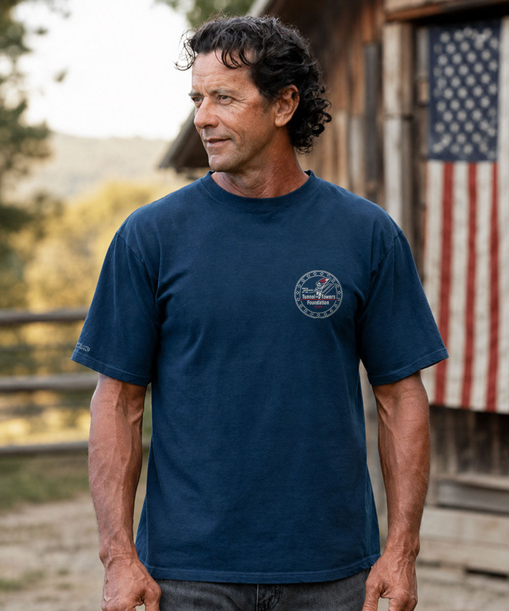 A man wearing a navy blue crewneck t-shirt with a circular 'The Powerpuff Girls' logo on the left chest, standing outdoors in front of a house View 3
