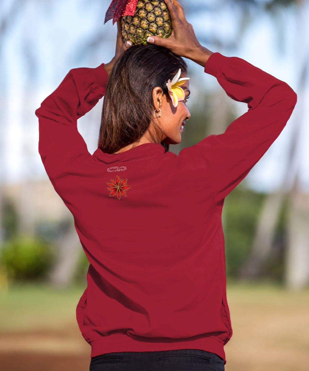A woman outdoors wearing a red sweatshirt, seen from behind as she balances a pineapple on her head. The sweatshirt has a small orange and yellow sunburst graphic on the left shoulder and a small white script logo on the back neck. View 3