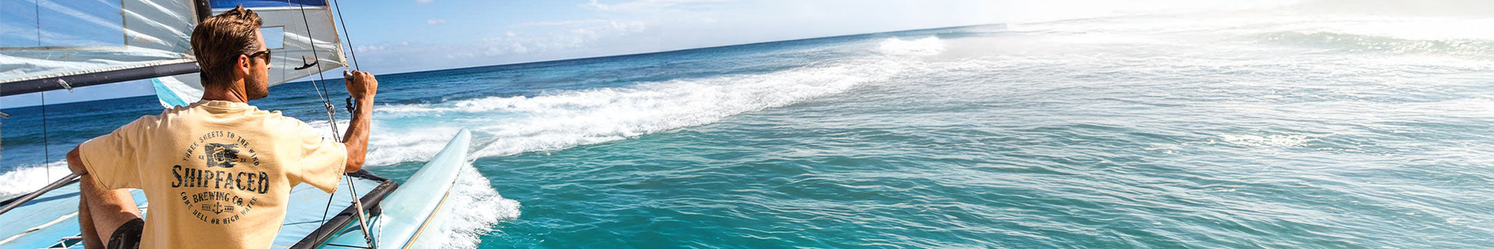 Person on a sailboat in the ocean with clear blue water and sky.