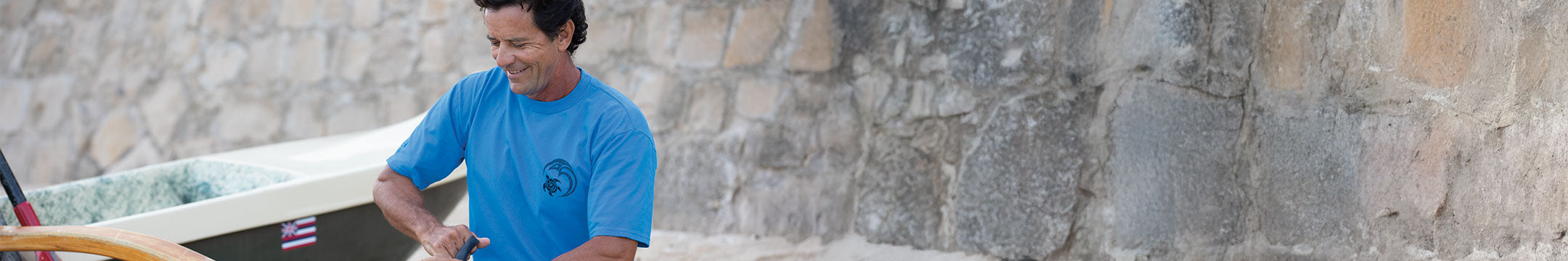 Person wearing a blue shirt standing next to a stone wall