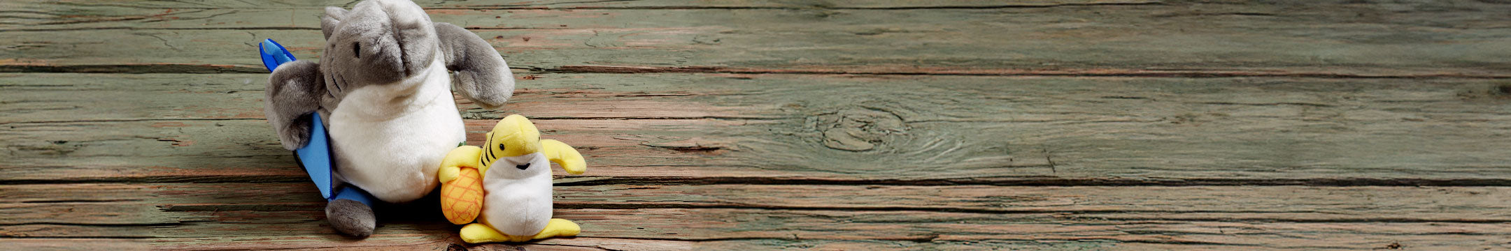 Two Sharka stuffed animals, on a wooden surface.