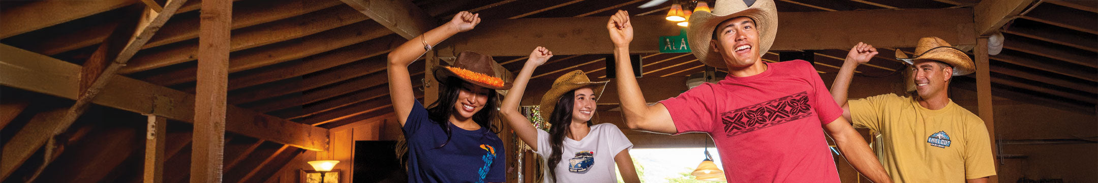 Four people celebrating indoors with arms raised, wearing cowboy hats and Crazy Shirt Tees.