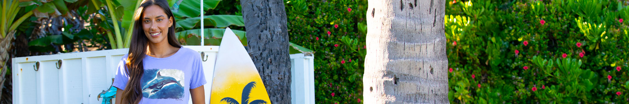 Woman holding a surfboard with a dolphin design in a tropical setting 