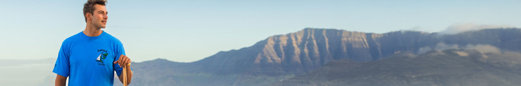 Man in a blue shirt standing with mountains in the background