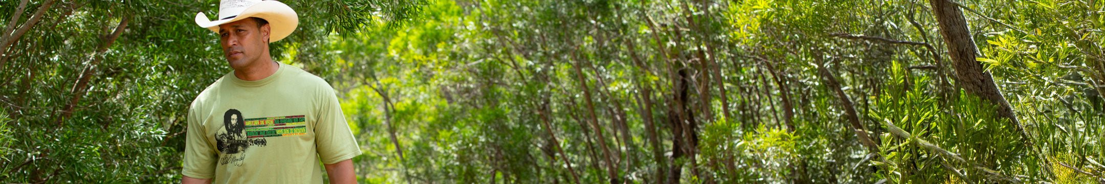 Man wearing a cowboy hat and green t-shirt with a logo in a forest setting
