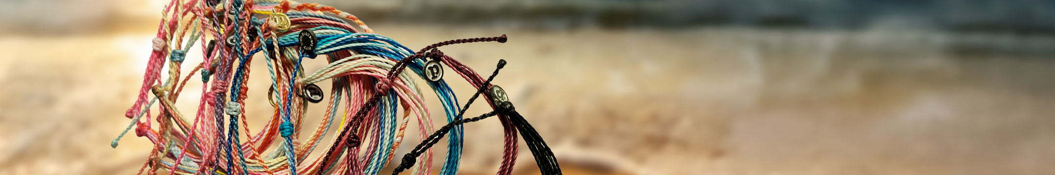 Close up shot of Pura Vida bracelets on a beach backdrop
