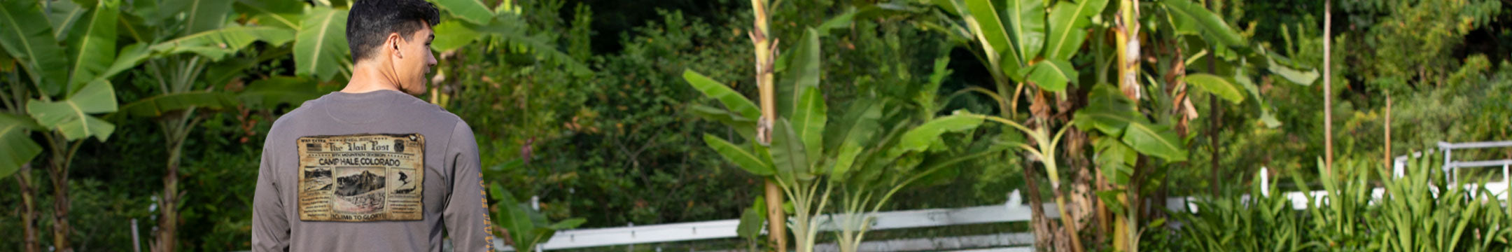 Person standing in a lush green garden with trees and plants around
