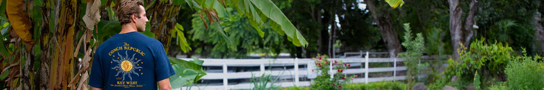 Person wearing a blue t-shirt with text and graphics in a garden setting