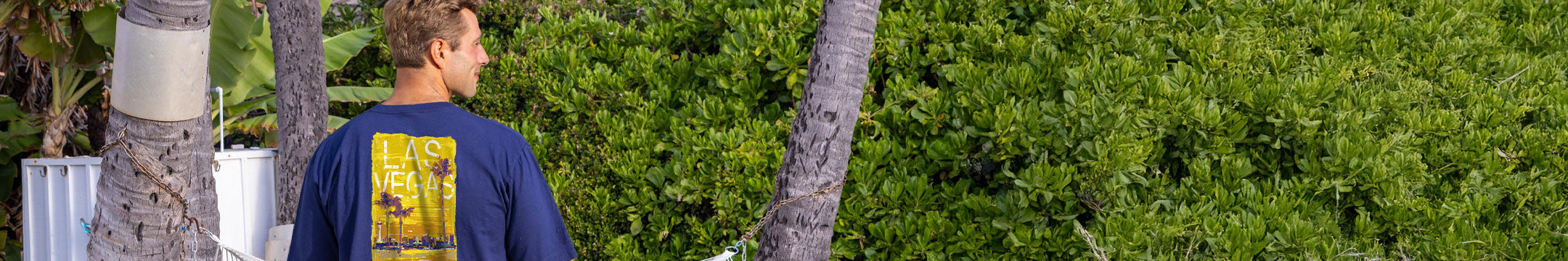 Man walking through a tropical forest with palm trees and greenery.