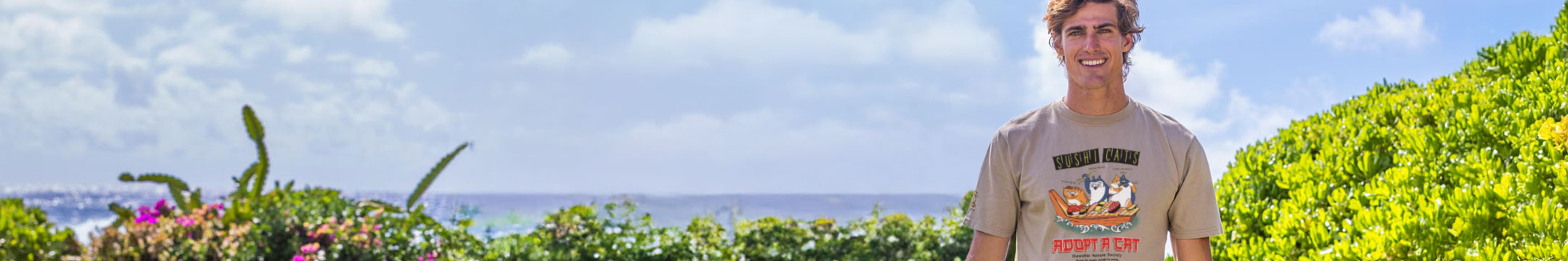Person standing in a scenic location with ocean and greenery
