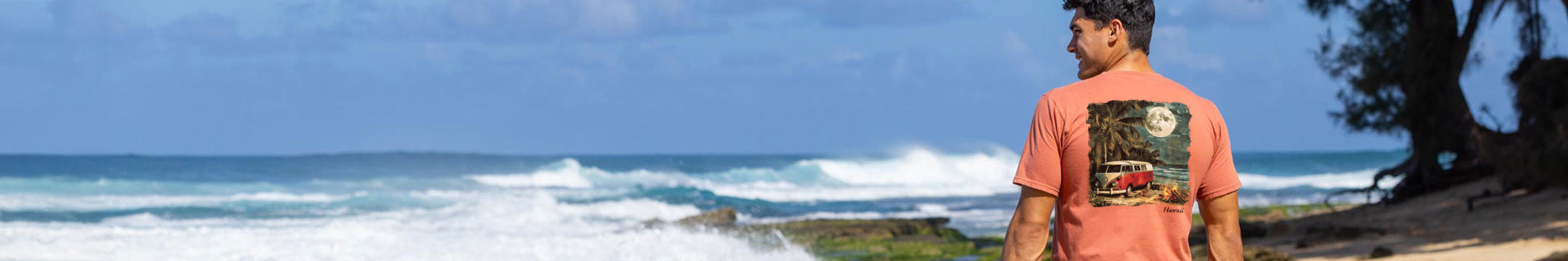 Man wearing a t-shirt with a graphic design standing on a beach.