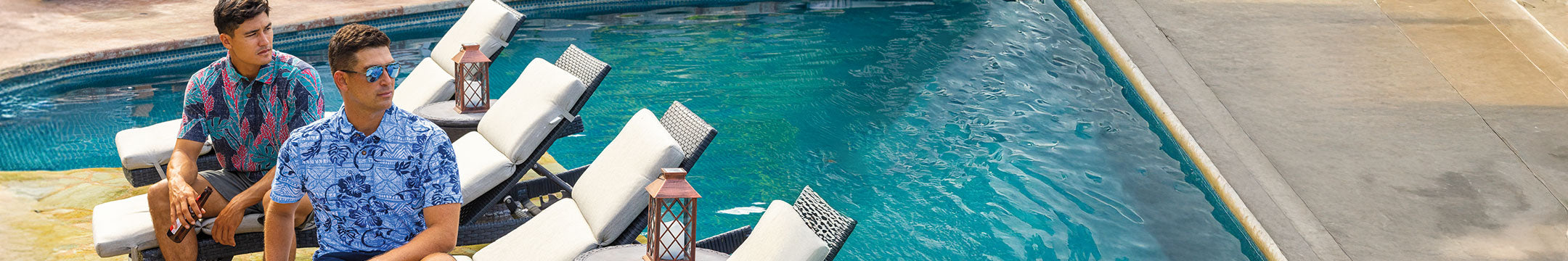 Two men sitting by a pool with lounge chairs and a guitar