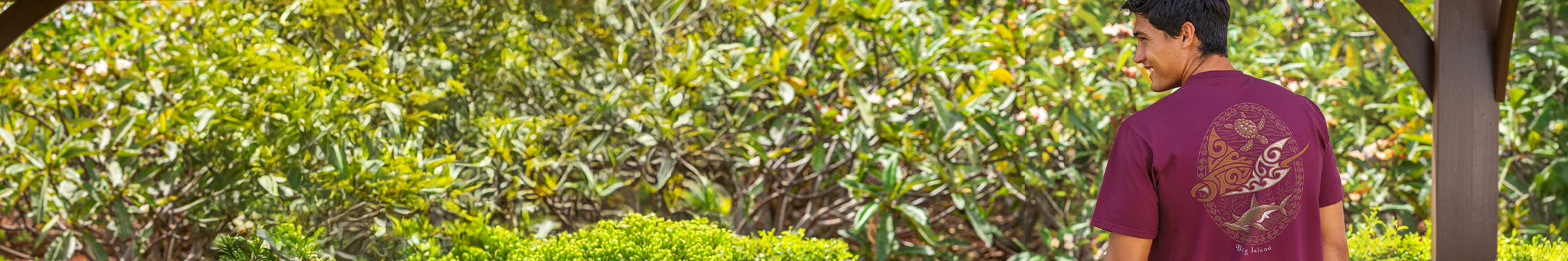 Man wearing Wine Dyed Tee walking through a lush green forest