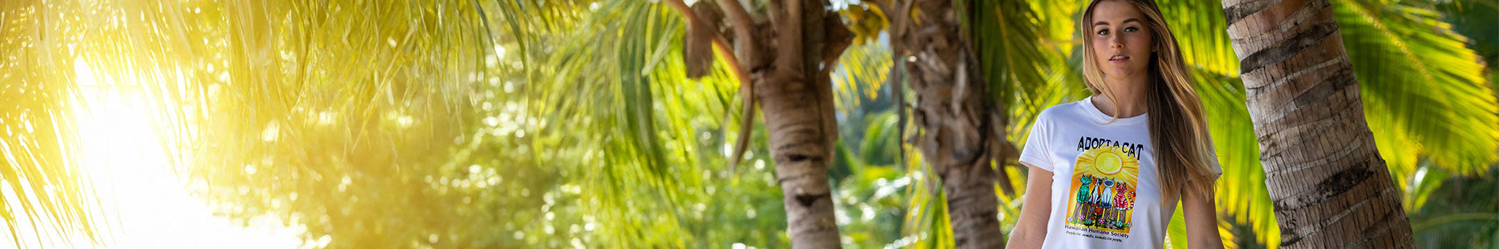 Woman standing among palm trees with a bright sun in the background