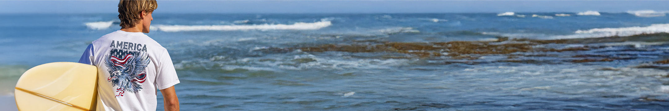 Person with a surfboard looking out at the ocean
