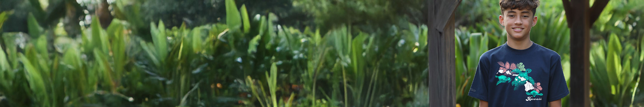 Young boy standing in a garden with greenery, wearing a crazy shirts tee