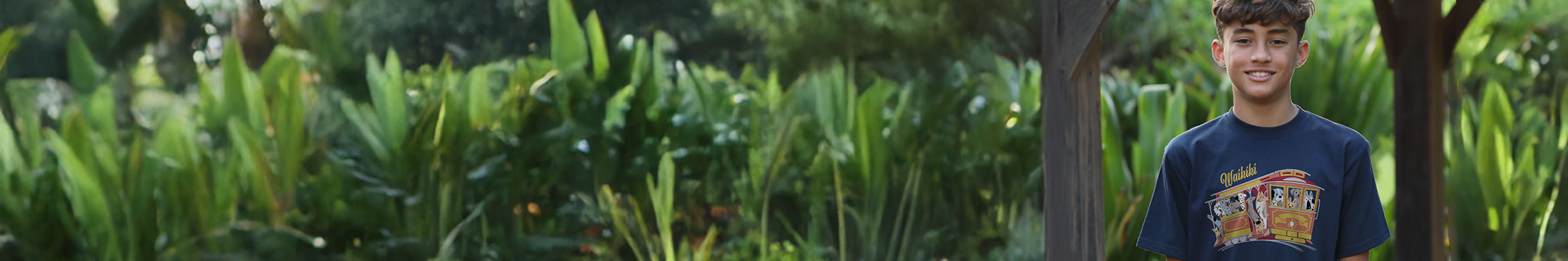 Young boy wearing a blue t-shirt with a graphic design in a garden setting