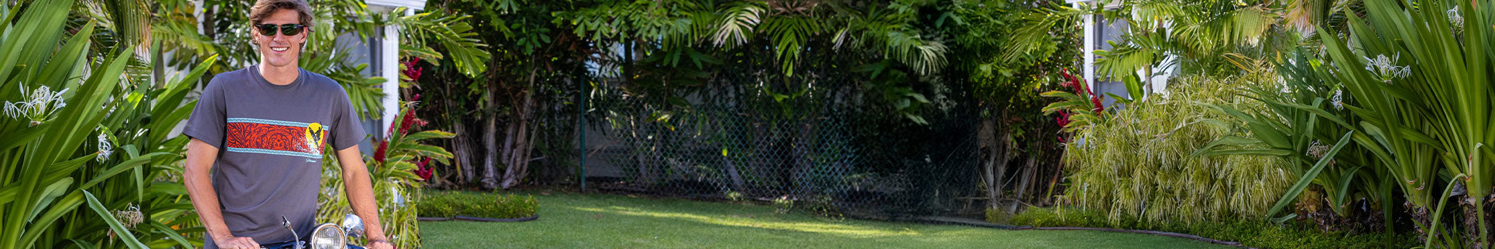 Man standing in a garden with lush greenery, wearing a crazy shirts pima tee