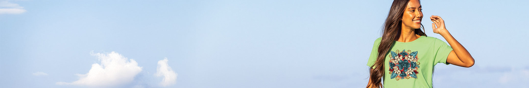 Woman wearing a green t-shirt with a graphic design against a clear blue sky.