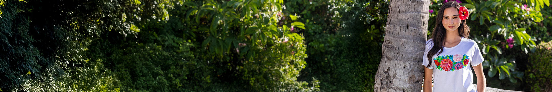 Woman standing outdoors with greenery and a palm tree in the background