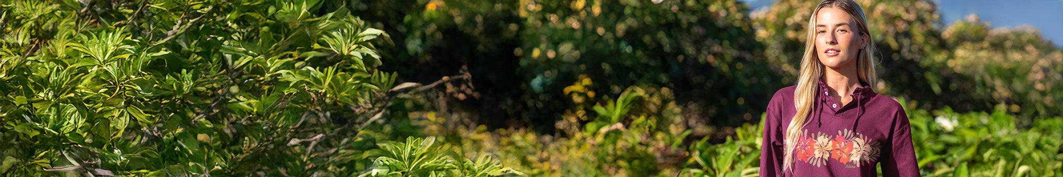 Woman standing in a lush green field with trees and plants around