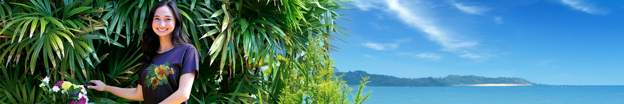 Woman sitting among tropical plants with a scenic ocean view in the background