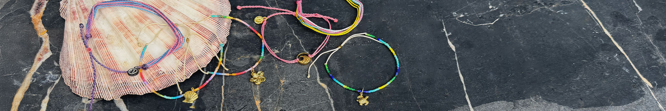 Colorful bracelets on a black surface with a shell