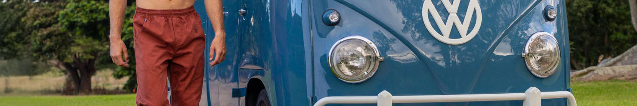 Person wearing red pants standing next to a blue Volkswagen van.