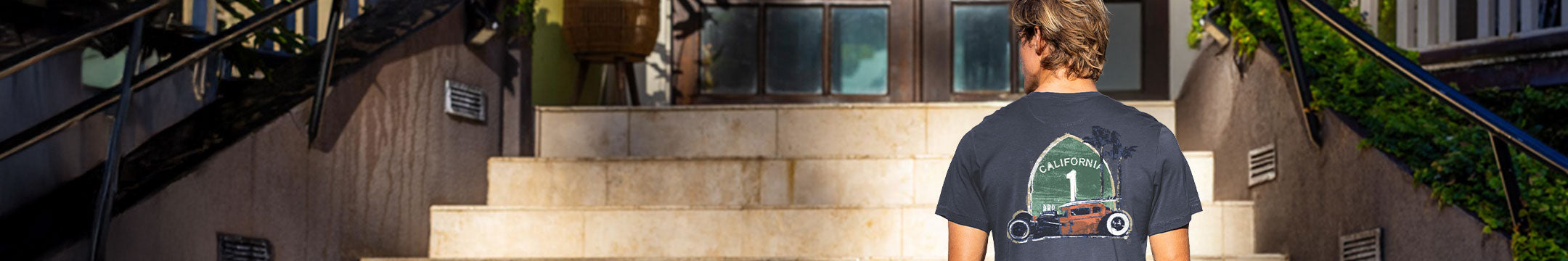 Person wearing a t-shirt with a graphic design, standing on a staircase.