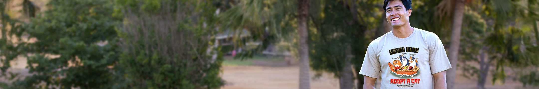 Man wearing a t-shirt with a adopt-a-cat graphic design outdoors