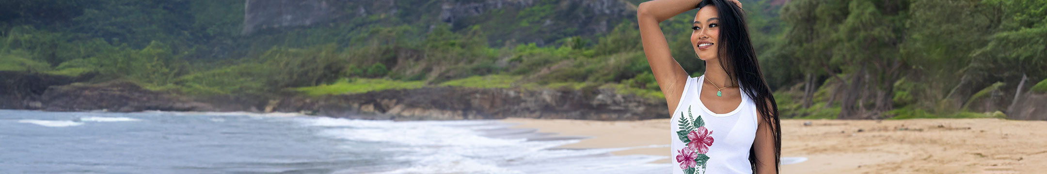 Woman standing on a beach with ocean and greenery in the background