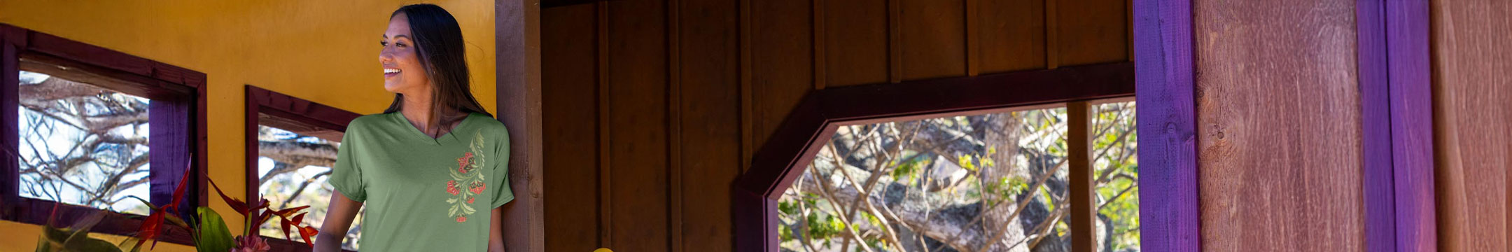 Woman in a green shirt standing in a room with wooden walls and a window view.