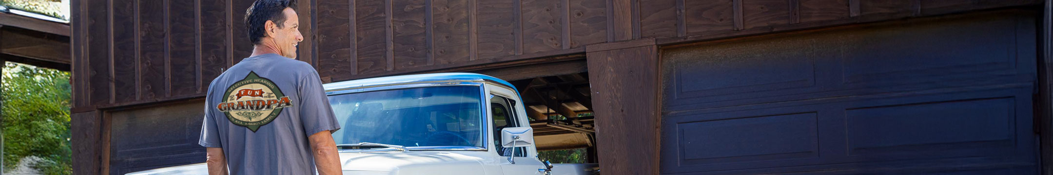 Man standing next to a white truck under a wooden overpass